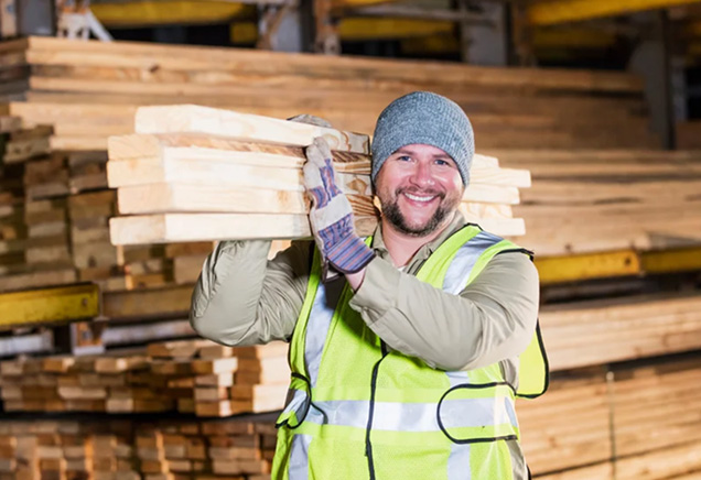 Lumberyard worker carrying a stack of wood boards at Tri-City Lumber in Kennewick, WA.